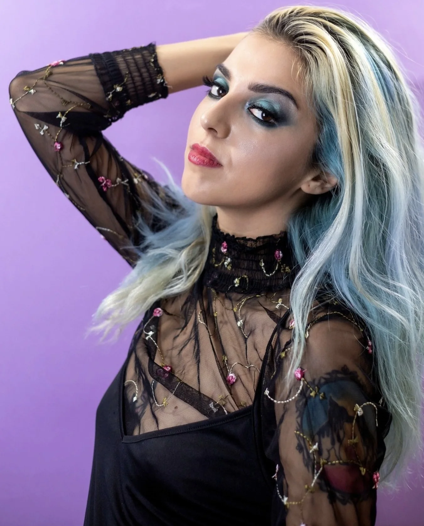 Ritratto fashion con make-up blu su sfondo viola